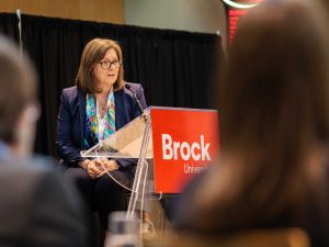 A woman speaks from a podium at an event.