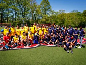 A large group of people in soccer uniforms pose for a photo in a field.