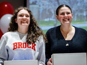 Two Niagara Principal’s Scholarship recipients smile while holding their Brock welcome boxes during the award ceremony.