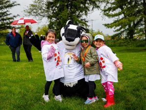 Three children pose with Brock University’s Boomer the Badger mascot during the rainy Rankin Cancer Run event.