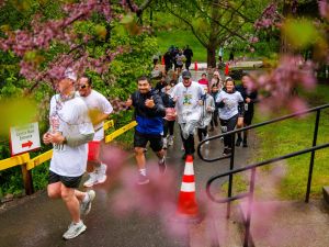 Rankin Cancer Run participants make their way along a wet campus path framed by spring blossoms and greenery.