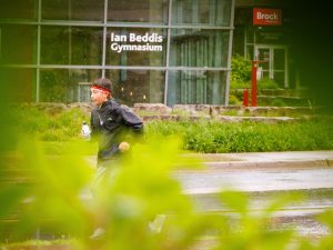 A runner passes the Ian Beddis Gymnasium at Brock University during the rainy Rankin Cancer Run.