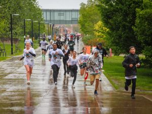 Rankin Cancer Run participants run along a rain-soaked Brock University walkway lined with trees and campus buildings.