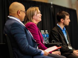 Three people sit on stage during a panel discussion.