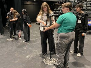 Students practice using big lights on a stage in a theatre.