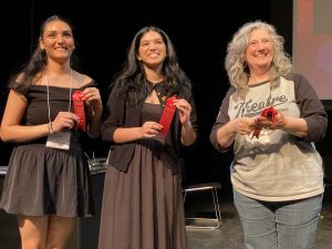 A woman hands two students awards.