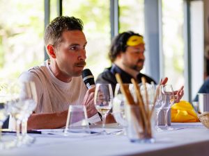 Two men sit at a table addressing a crowd.