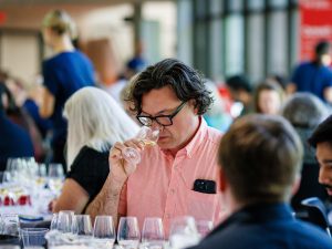 People taste wine sitting at round tables.