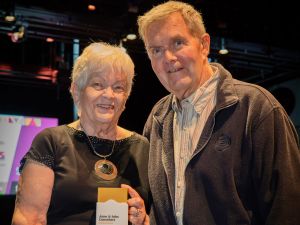 A woman and a man stand together smiling holding an award.