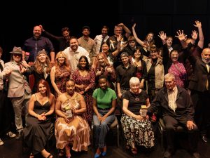 A large group of people stand together smiling.