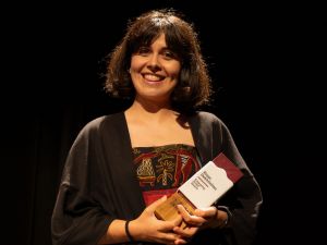 A woman smiles holding an award.