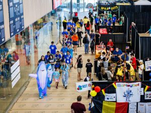 Crowds of participants are walking around the pit area of the robotics competition.