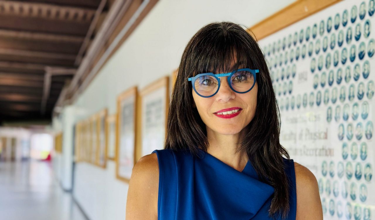 A woman stands in a university hallway smiling.