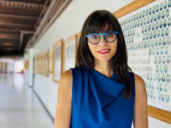 A woman stands in a university hallway smiling.