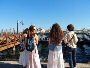 A group of people stand on a pier looking at small boats.