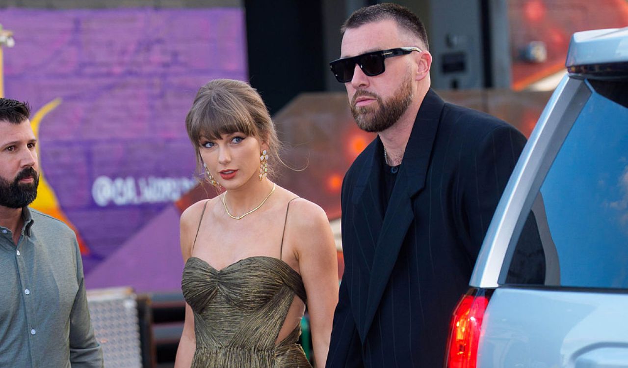 Taylor Swift and Travis Kelce are seen walking hand in hand outside.