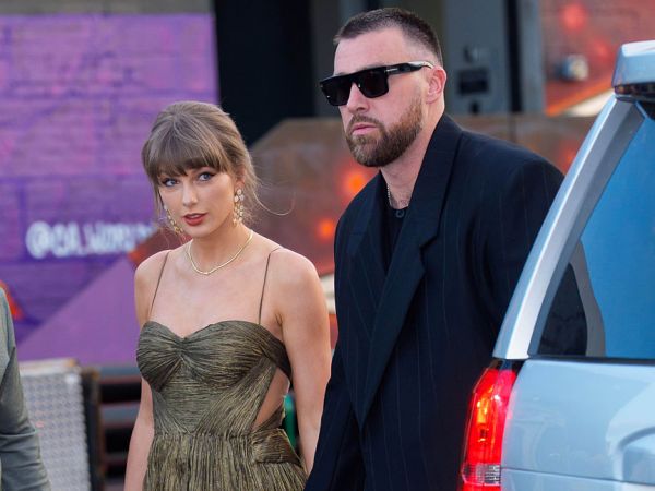 Taylor Swift and Travis Kelce are seen walking hand in hand outside.