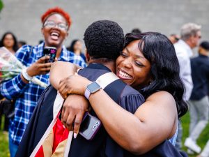 A new university graduate hugs a loved one after a graduation ceremony.