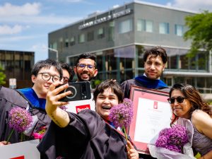 A group of university graduates and loved ones pose for a selfie.