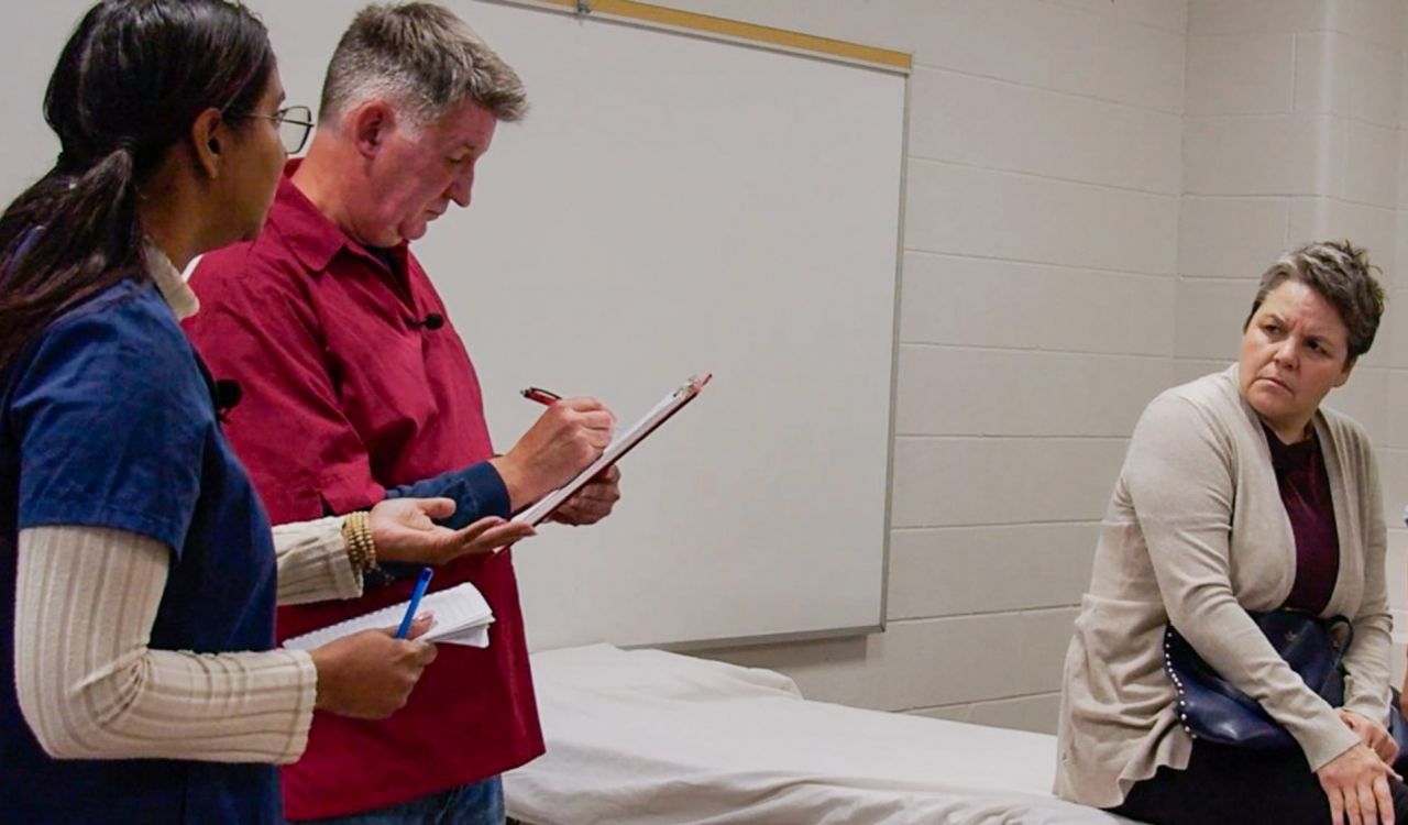 Four people acting as patients and health-care workers perform a scene from a play.