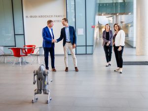 Four people stand together looking over a robotic dog.