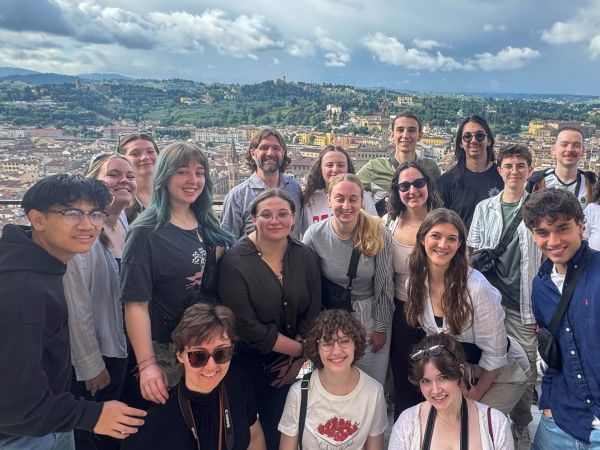 A group of people stand atop Duomo Santa Maria in Florence, Italy with a view of the Florence behind them.