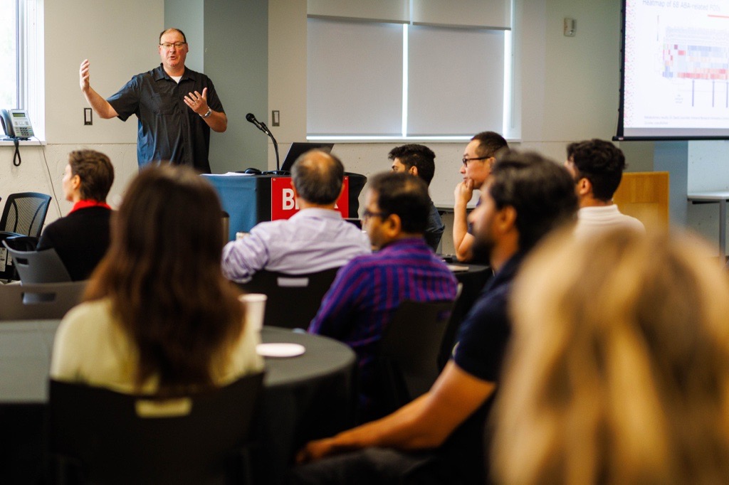 A man speaks to an audience from the front of a meeting room.