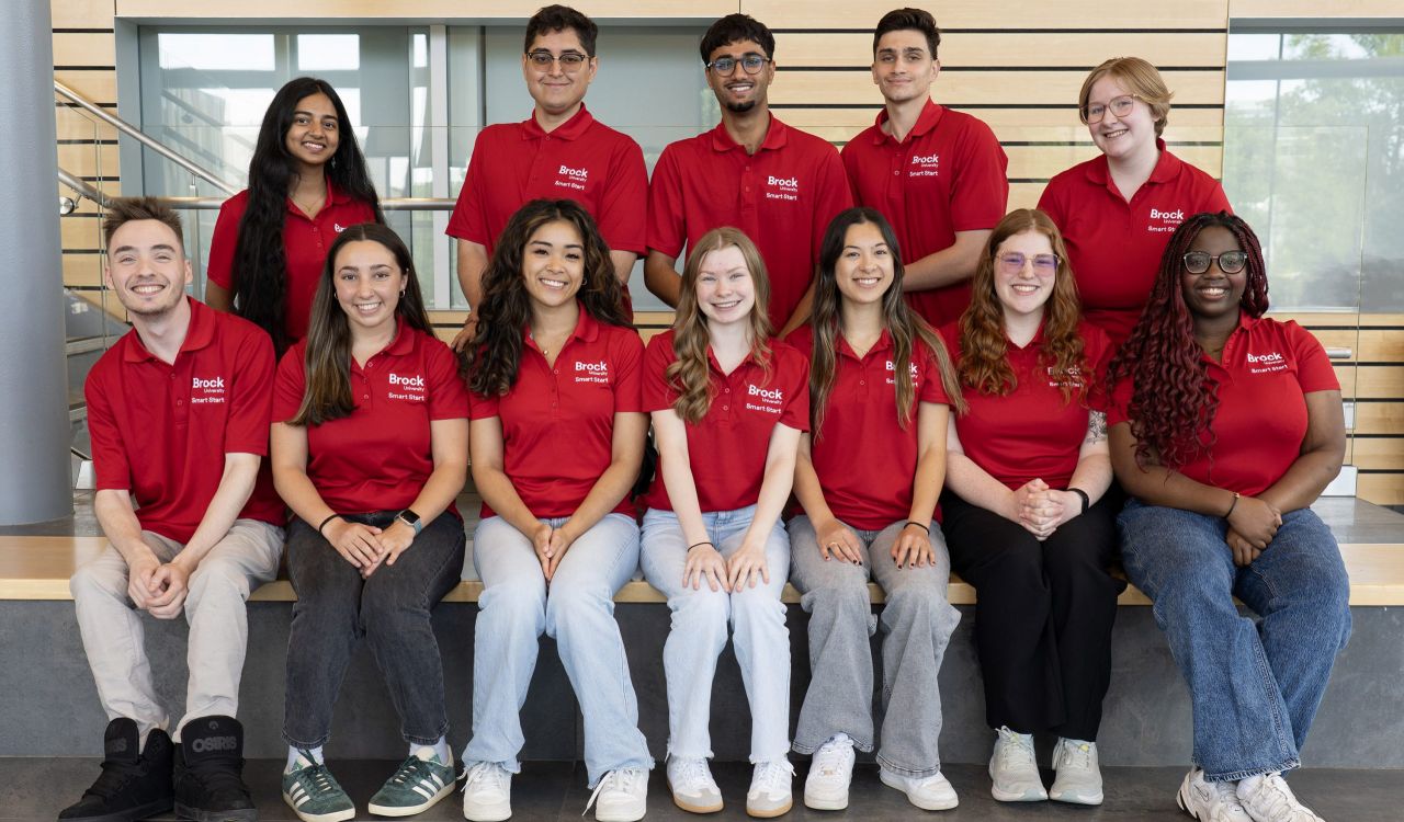 A group of people in red Brock University shirts gather together.