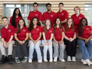 A group of people in red Brock University shirts gather together.