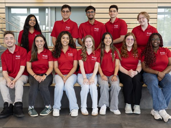 A group of people in red Brock University shirts gather together.