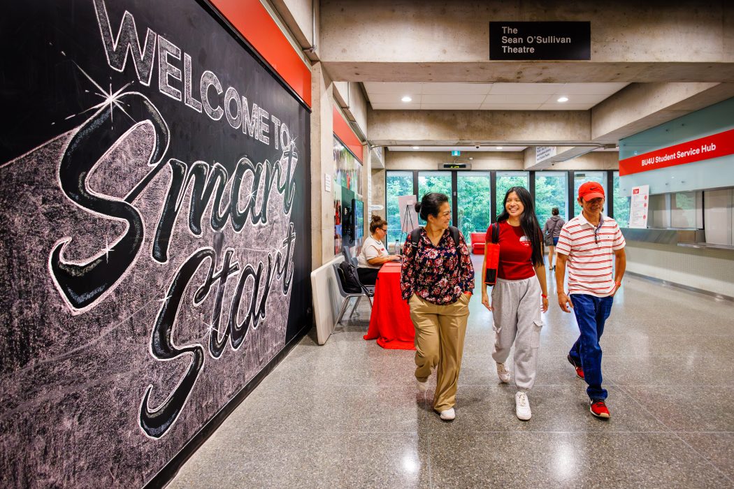 A university student walks down a hallway at Brock University with her parents.