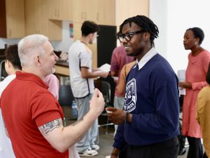 Two people have a conversation in a busy room at an event at Brock University.