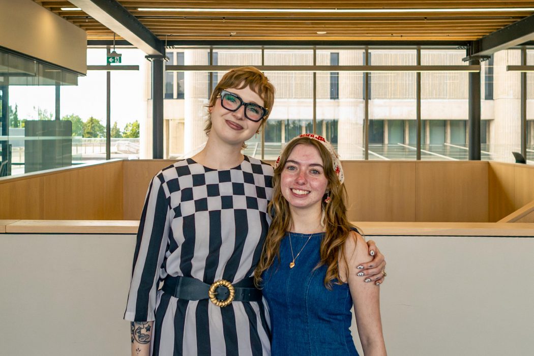 Sarah Godfrey and Emily Kotyk pose for a photo together in a bright atrium at Brock University.