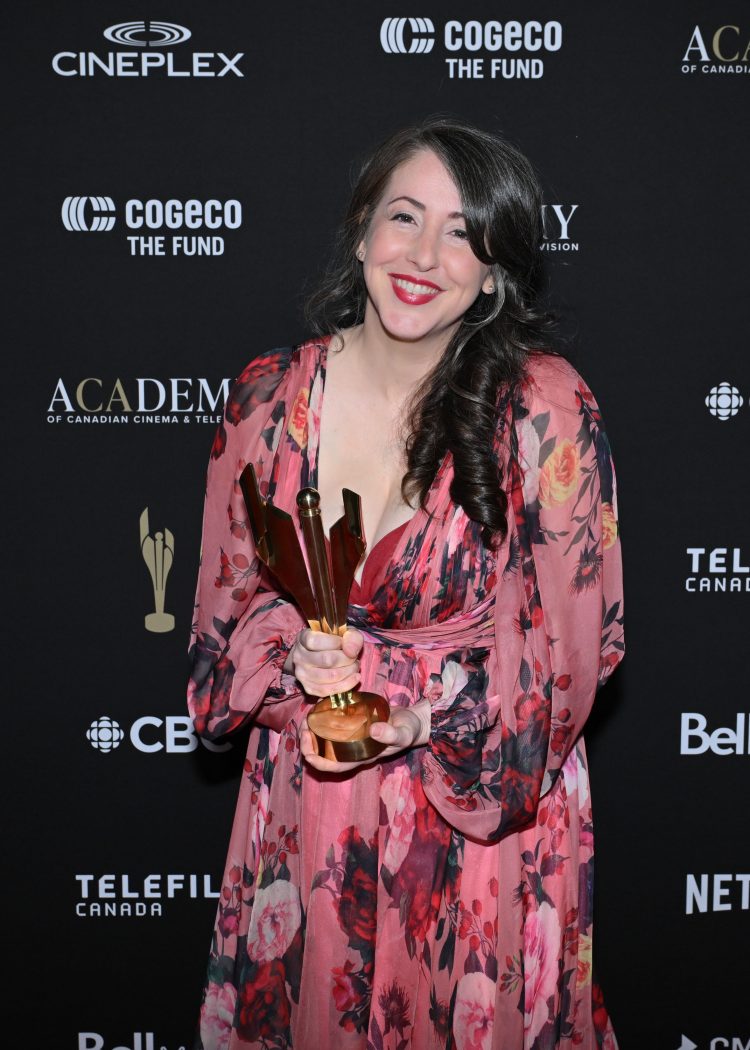 A woman smiles at the camera holding an award.