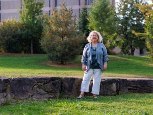 A woman poses for a photo while standing in a green space in front of a concrete tower.