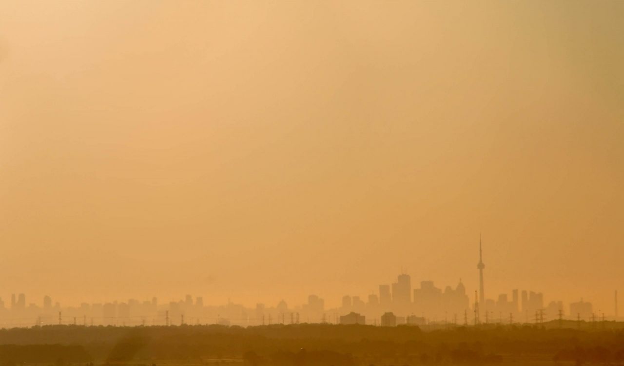 A view of the Toronto skyline under a hazy orange sky.