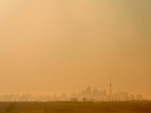 A view of the Toronto skyline under a hazy orange sky.