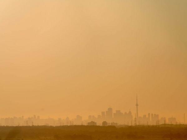 A view of the Toronto skyline under a hazy orange sky.