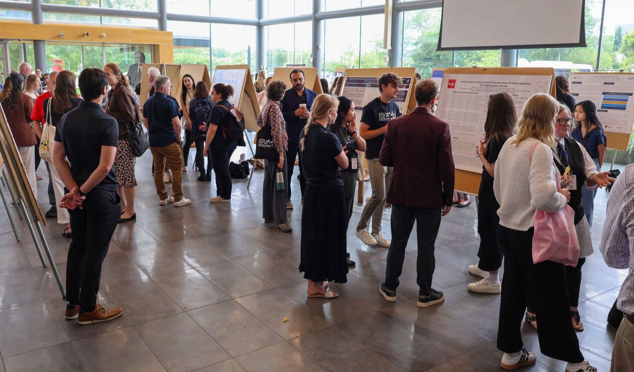 A large crowd of researchers views posters in the Goodman Atrium.