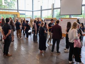 A large crowd of researchers views posters in the Goodman Atrium.
