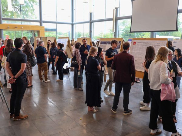 A large crowd of researchers views posters in the Goodman Atrium.