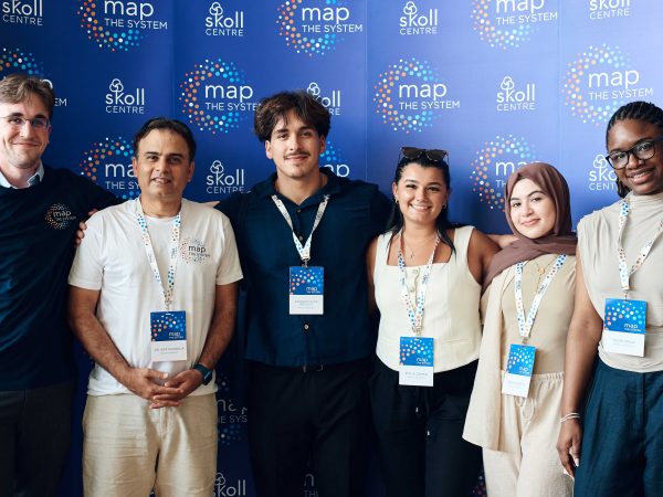 Five university students and a professor stand together in front of a blue backdrop.