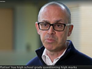 A man speaks to a camera, which is not visible, during a news interview.
