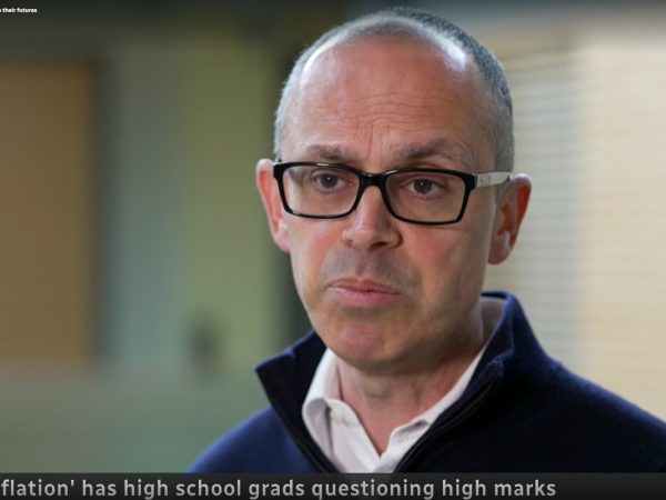A man speaks to a camera, which is not visible, during a news interview.