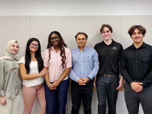 Six people stand together smiling.
