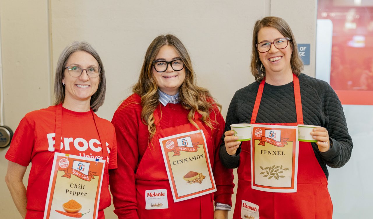 Three people in red aprons pose for a photo at a fundraising event.