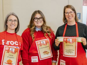 Three people in red aprons pose for a photo at a fundraising event.