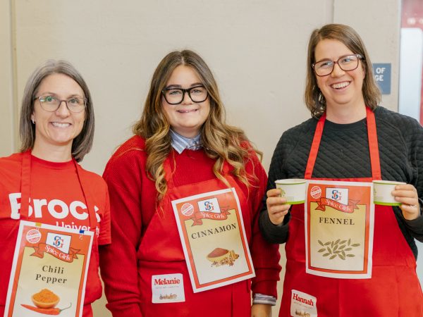 Three people in red aprons pose for a photo at a fundraising event.
