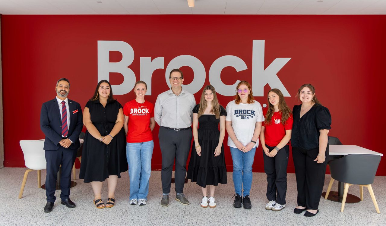 A group of Brock students stand in a line with MP Chris Bittle in the atrium of Brock’s main campus.