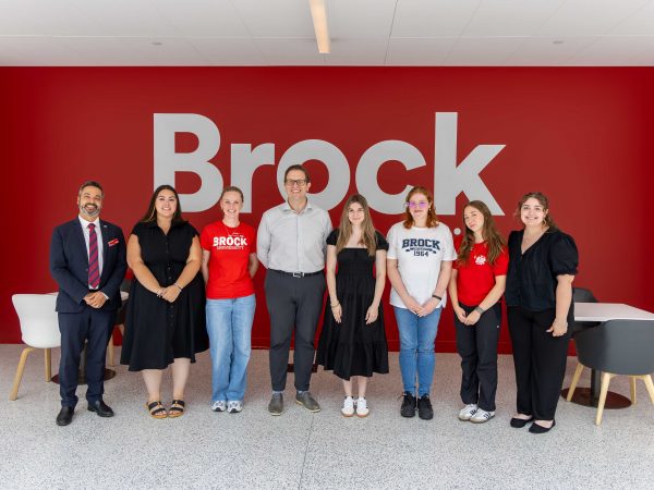 A group of Brock students stand in a line with MP Chris Bittle in the atrium of Brock’s main campus.